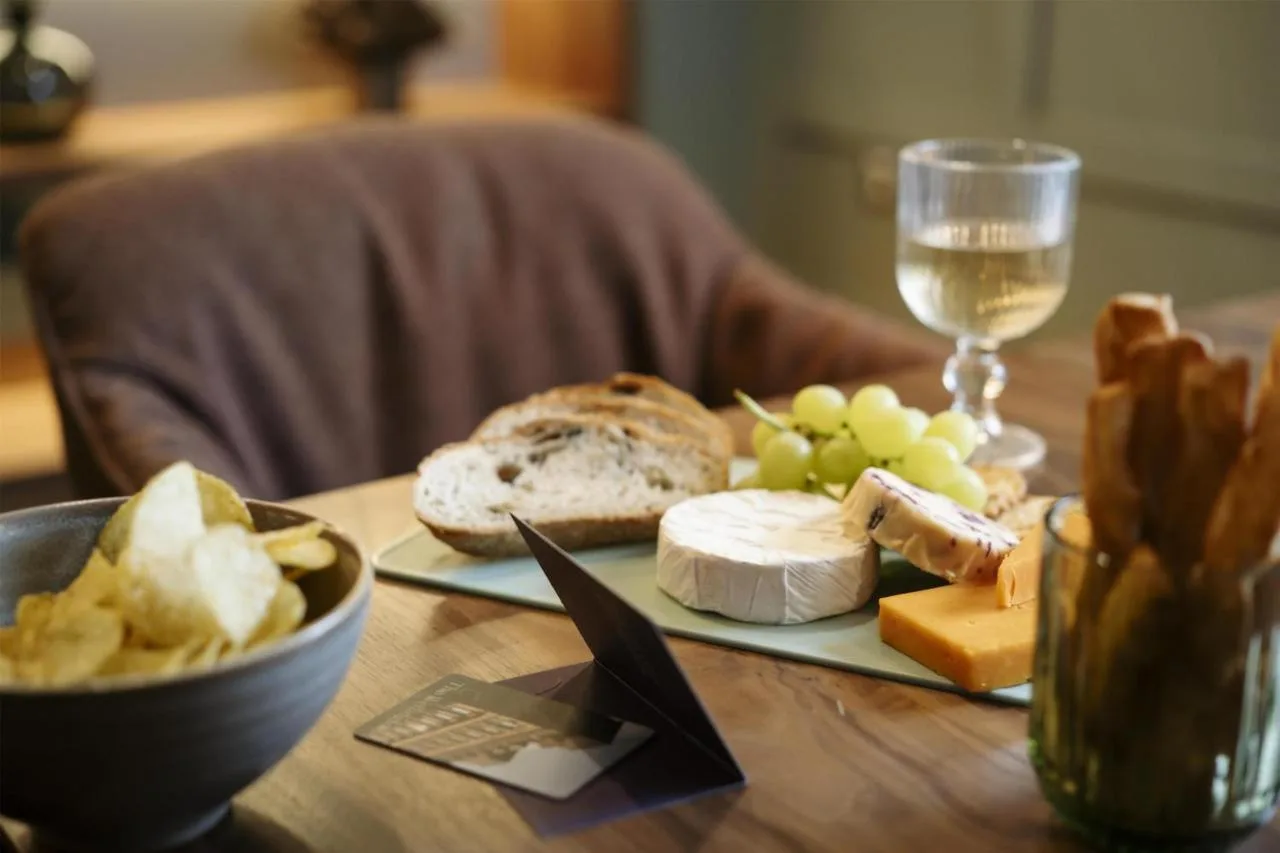 A plate of cheese and a glass of wine on a table at The Wellington Glasgow by Adina